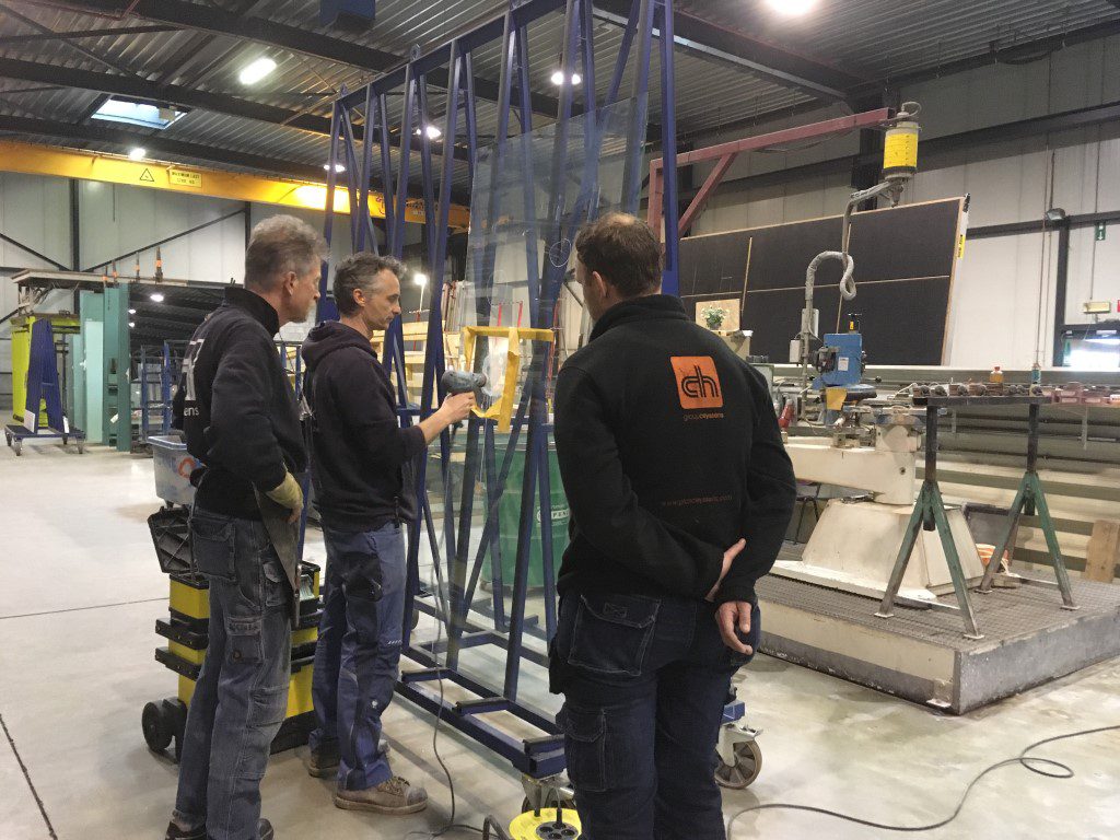 Twee medewerkers in VitroWorks-jas in het atelier, tussen rekken met glasplaten