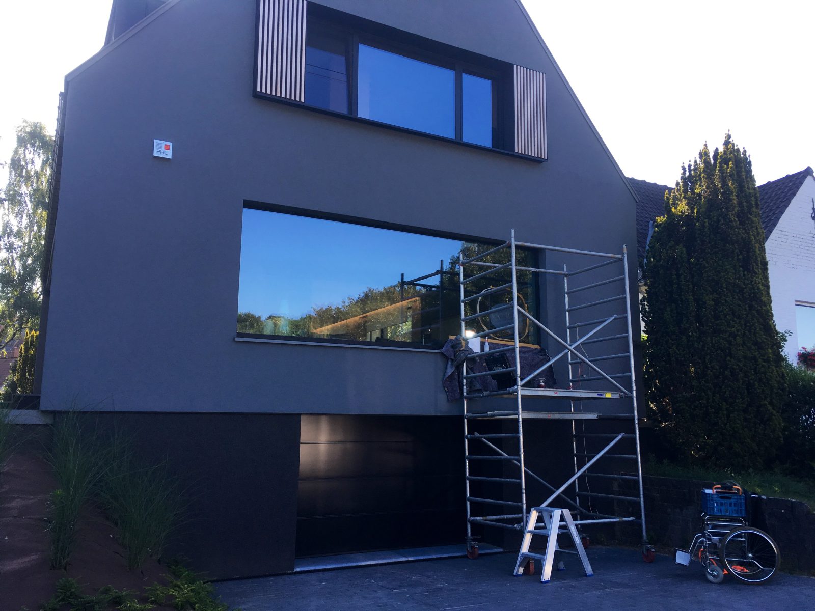 Moderne donkere woning met een grote raampartij, met een rolsteiger ervoor opgesteld