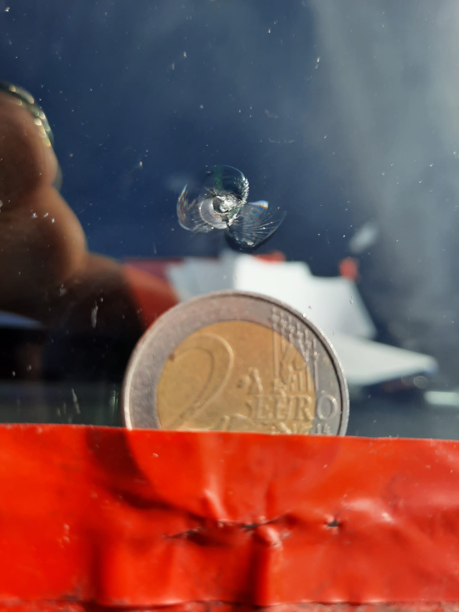 Muntstuk naast een sterretje in een autoruit, waardoor de grootte van de schade meteen duidelijk wordt